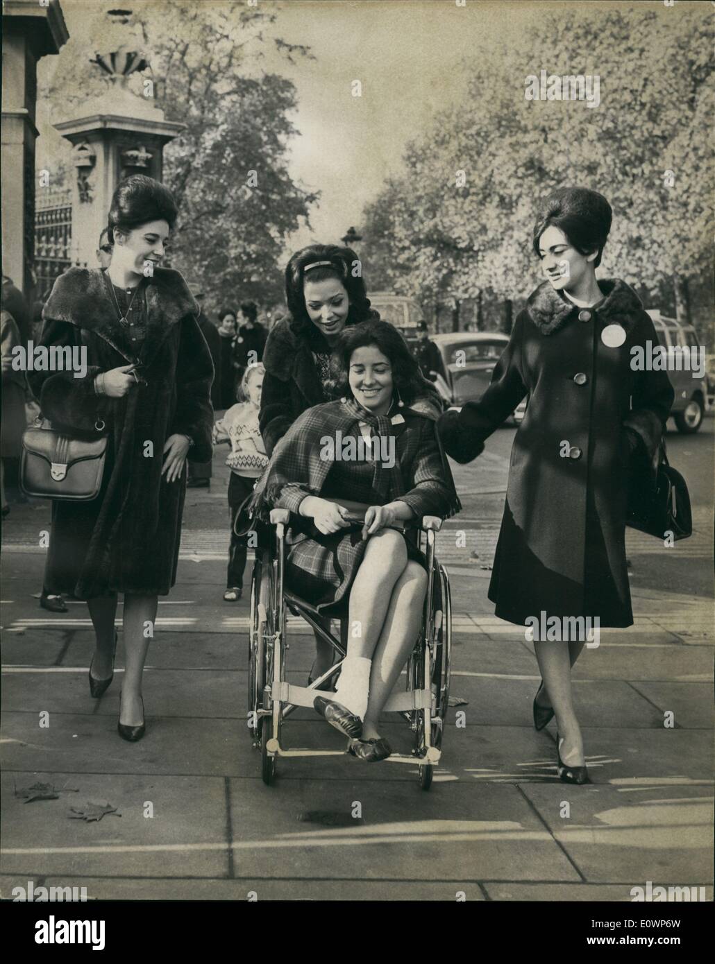 11 novembre 1963 - Investiture de Miss Monde assister à la relève de la garde aujourd'hui : les participants au concours Miss Monde ce matin est allé au palais de Buckingham pour assister à la relève de la garde. Photo montre au palais ce matin L À R Mlle argentines (Diana Sart), Miss Mexique (Beatriz Solorzano) et Mlle Boliva Lopera (Rosario) pousser Miss Espagne (Encarnacion Zalabardo), dans un fauteuil roulant. Elle s'est foulé la cheville lors d'une réception hier soir. Banque D'Images