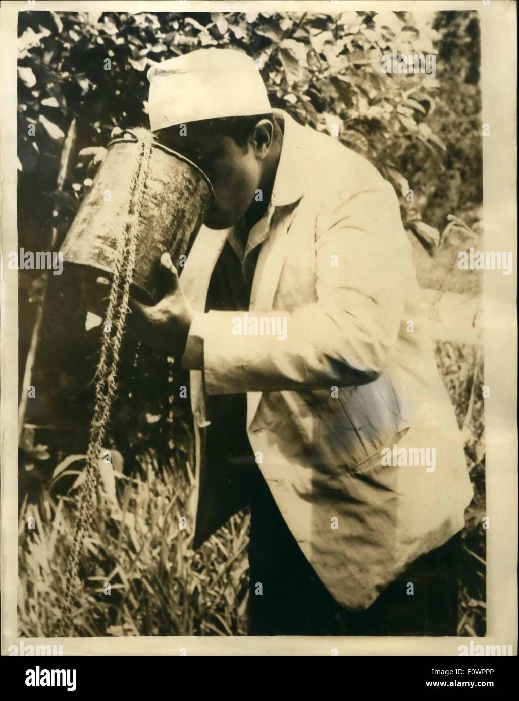 11 novembre 1963 - Le sultan des boissons dans un seau. Seyyid Jamshid Bin Abdullah, le jeune nouveau Sultan de Zanzibar, a récemment conduit une partie des 500 sur son passe-temps favori, une expédition de chasse de porcs sauvages, dans la forêt de Jozani, à environ 20 milles de la ville de Zanzibar. Le Sultan est un bon coup et a tué jusqu'à 75 porcs dans un seul voyage. C'était son premier voyage tat il a été capable de faire depuis la mort de son père. Photo montre :- Au cours d'un voyage dans la forêt, le parti, dont le Sultan, leur soif étanchée en abaissant un seau dans un puits et l'eau potable Banque D'Images