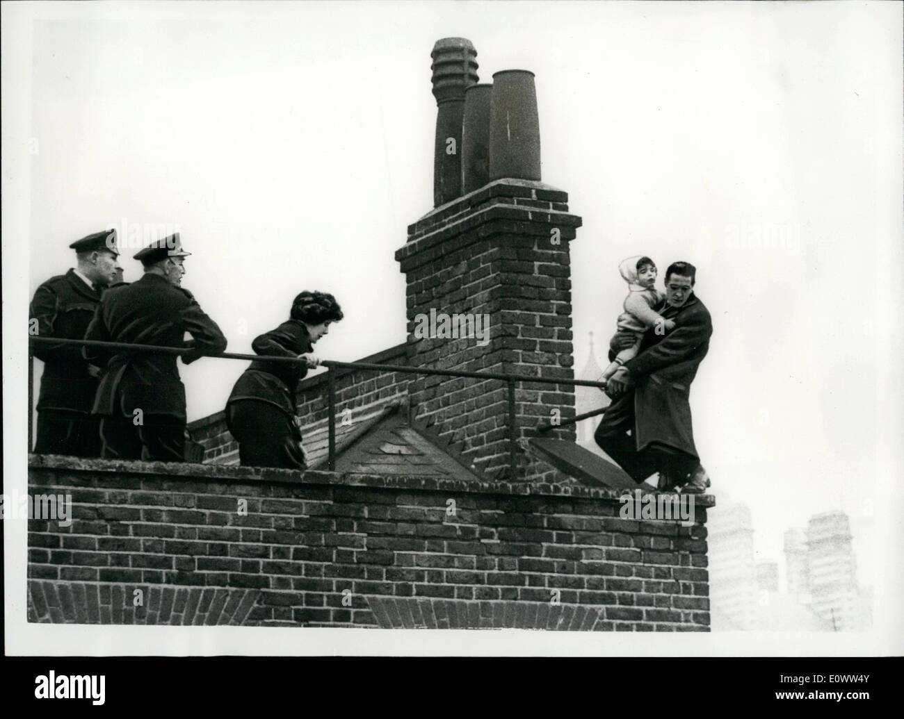 Mar. 03, 1964 - théâtre sur le toit à Bloomsbury : pour 85 minutes hier, alors que des centaines de personnes ont regardé d'en bas, 30 ans, Thomas était français sur un équilibre précaire en haut d'un immeuble de quatre étages de 60 pieds au-dessus de la rue à Bloomsbury, Londres, en tenant son 18-month-old fils Stewart dans ses bras, menaçant de sauter. Le français a dit qu'il avait été expulsé de son domicile, et que sa femme l'avait quitté. Pompiers et aides propagation des bâches ci-dessous, et trois policiers et d'une femme agent de police Margaret Cleland, 23, se sont réunis sur le toit et a essayé de raisonner avec l'homme Banque D'Images