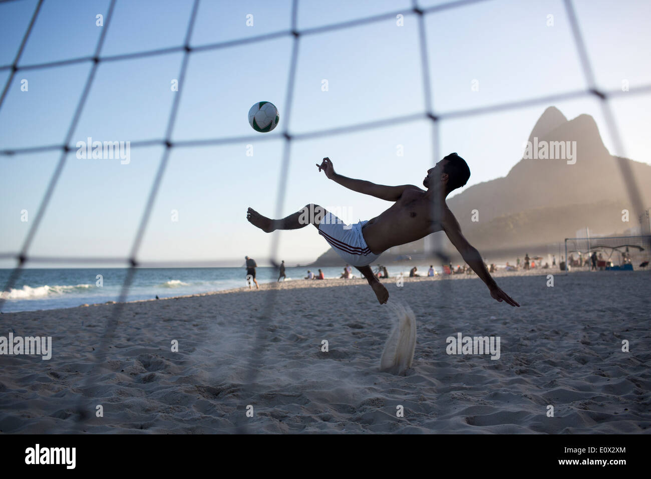 Un joueur marque un but acrobatically à partir d'une bicyclette overhead kick football sur la plage d'Ipanema à Rio de Janeiro, Brésil Banque D'Images