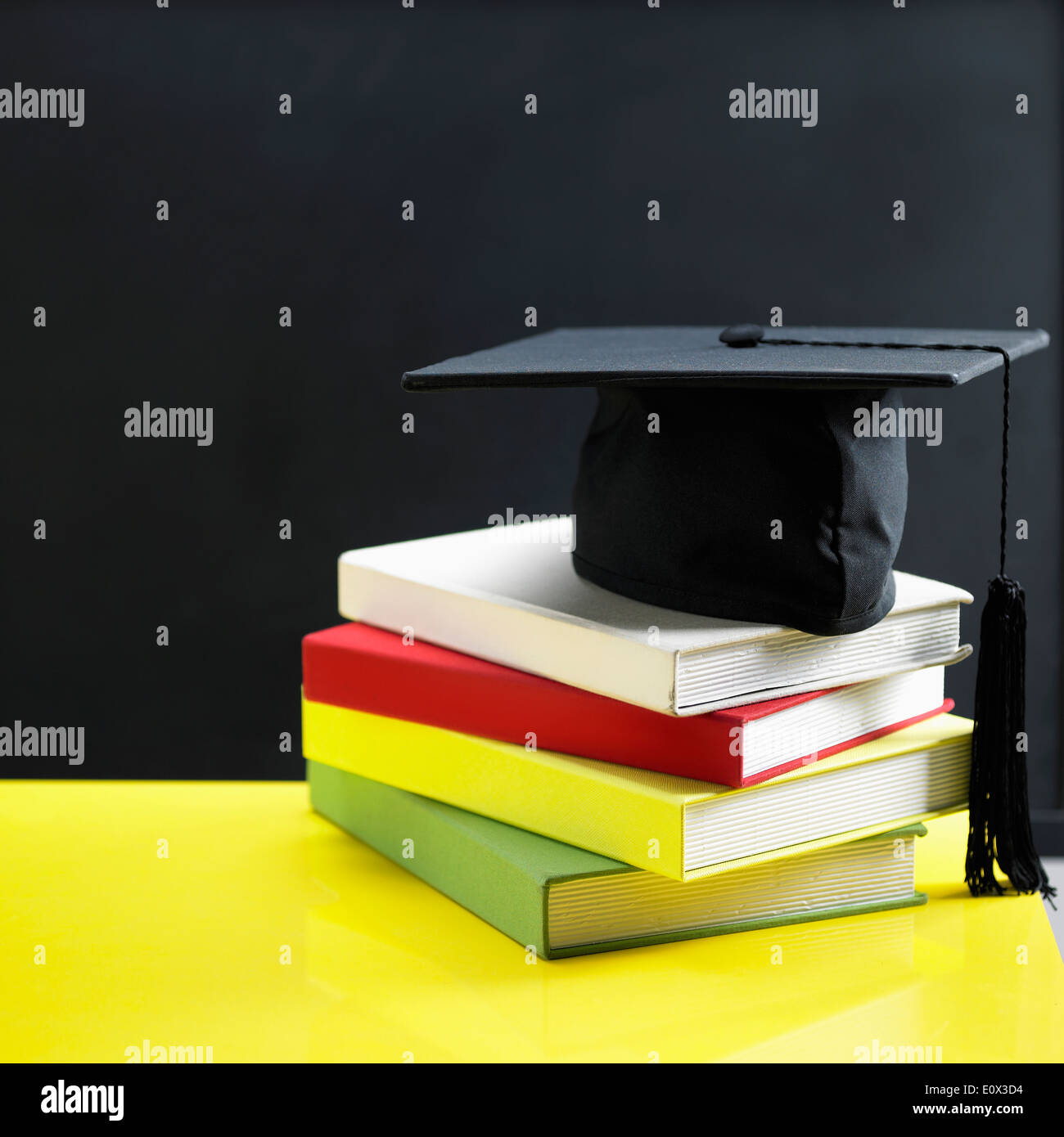 Une pile de livres et d'une graduation hat en face d'un tableau Banque D'Images