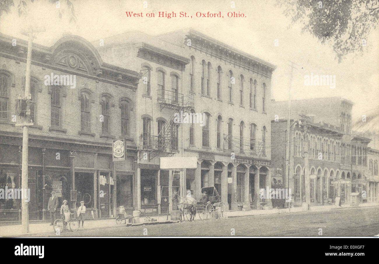 Cette image d'Oxford, Ohio, présente divers établissements commerciaux sur High Street, y compris des magasins vendant des vélos, des tricycles et des dévidoirs. La carte postale vintage met en valeur les entreprises locales et la vie quotidienne au cours de la période, reflétant la culture commerciale de la région. Banque D'Images