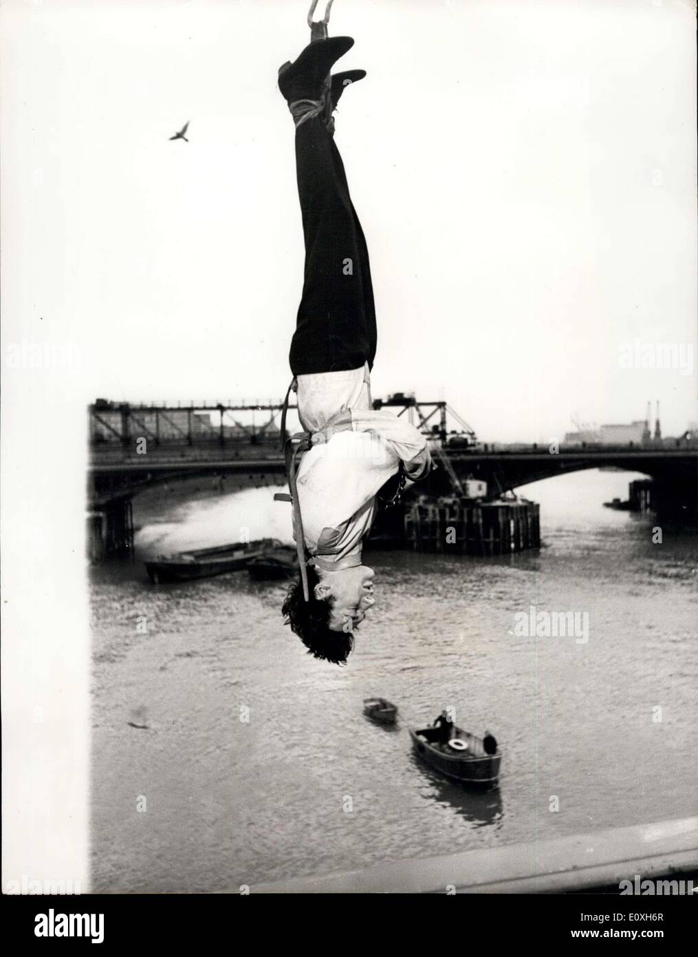 Le 19 décembre 1966 - défi Escapologist accepte de s'échapper d'une camisole de force si suspendu à l'envers sur Thames : Timothy Dill-Russell, conseiller l'assassin pour la comédie musicale "'Man of Magic'' au Piccadilly Theatre aujourd'hui a tenté un style Houdini échapper à un carcan alors que suspendu par ses talons à l'envers d'une grue sur la Tamise à Chelsea Bridge. Il a été mis au défi de le faire par Stuart Damon, qui joue de Houdini dans le spectacle. Photo montre Timothy Dill-Russell vu suspendu par ses talons au-dessus de la Tamise, au cours de sa fuite du corset et des menottes hier. Banque D'Images