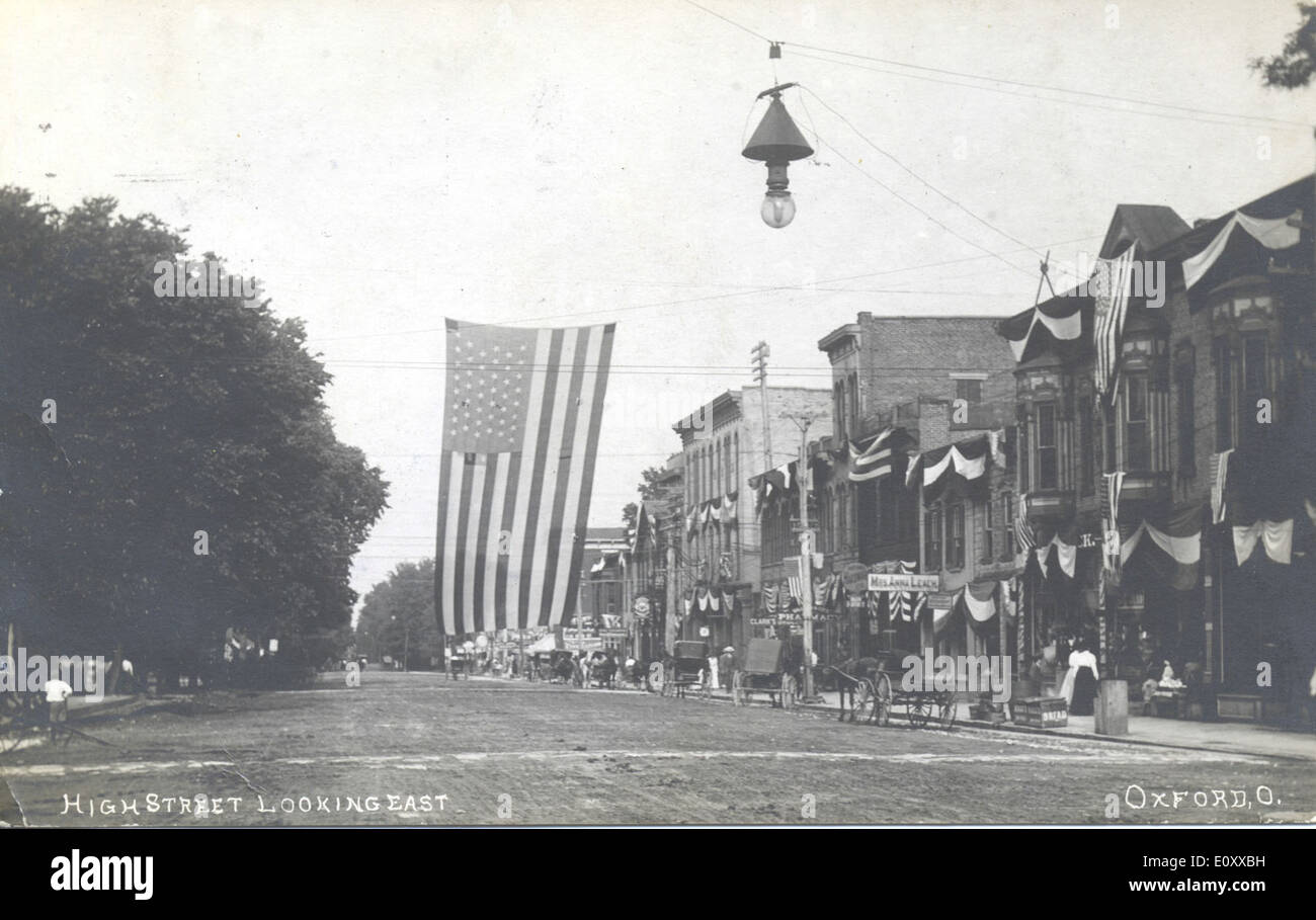 Cette carte postale capture une vue de High Street à Oxford, Ohio, regardant vers l'est, mettant en valeur la vie de la ville animée avec des magasins commerciaux et des magasins. L'image met en valeur l'atmosphère vibrante de la rue, avec des drapeaux et des boutiques visibles. Banque D'Images