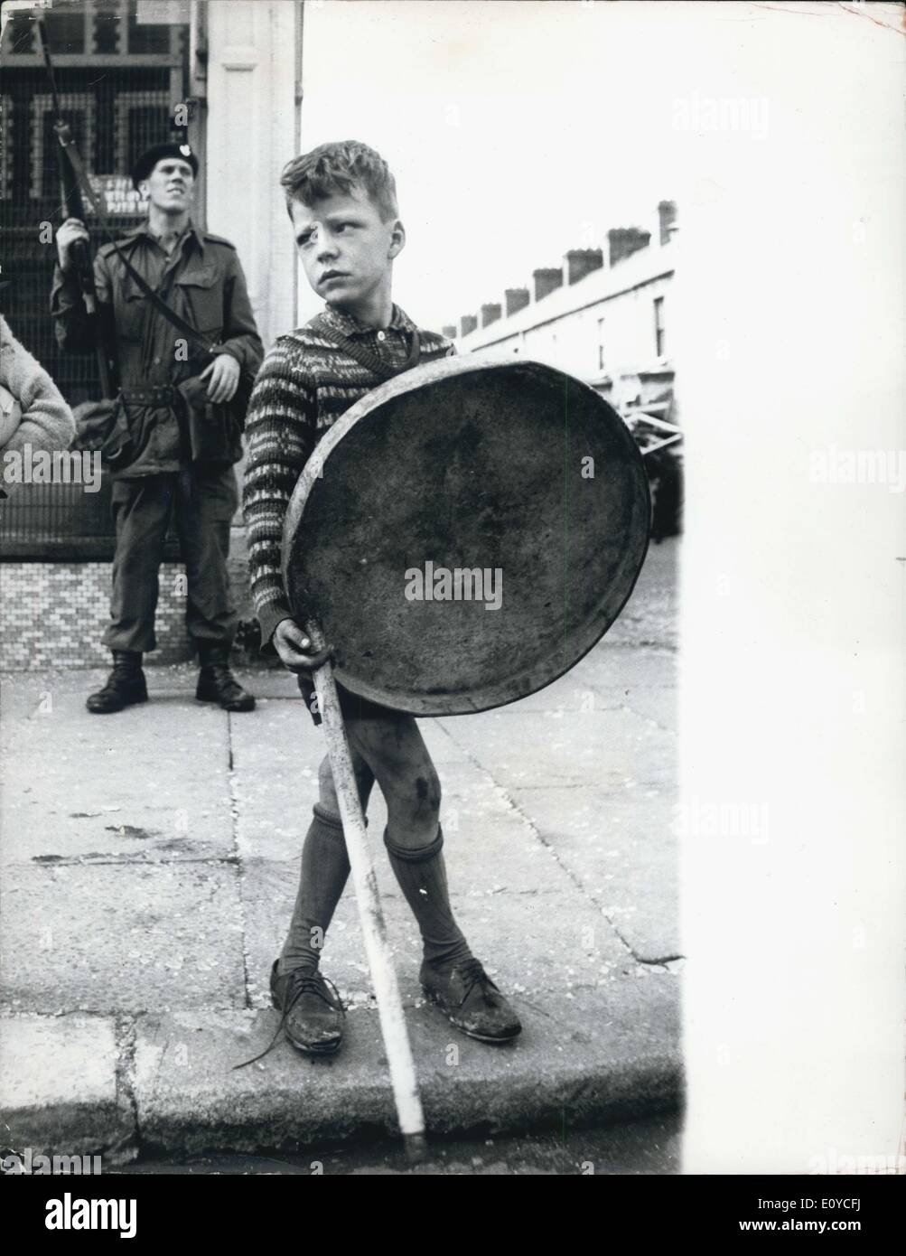 18 août 1969 - Les troupes britanniques à Belfast ; photo montre un soldat monte la garde en tant que petit garçon duetbin avec couvercle de protection et bâton, vient de derrière les barricades de regarder la rue dévastée, à Crumlin Road, Belfast. Banque D'Images