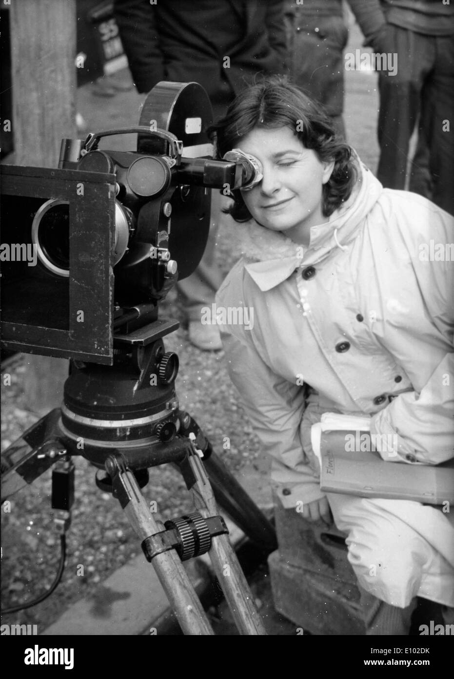 Femme en imperméable ressemble à travers l'objectif d'un appareil photo. Banque D'Images