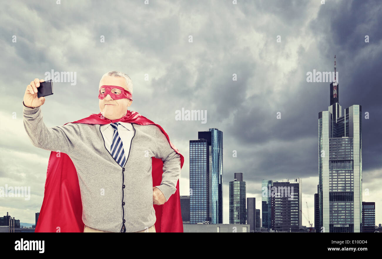Fier du super-héros mature prenant en selfies avant d'un dark city Banque D'Images