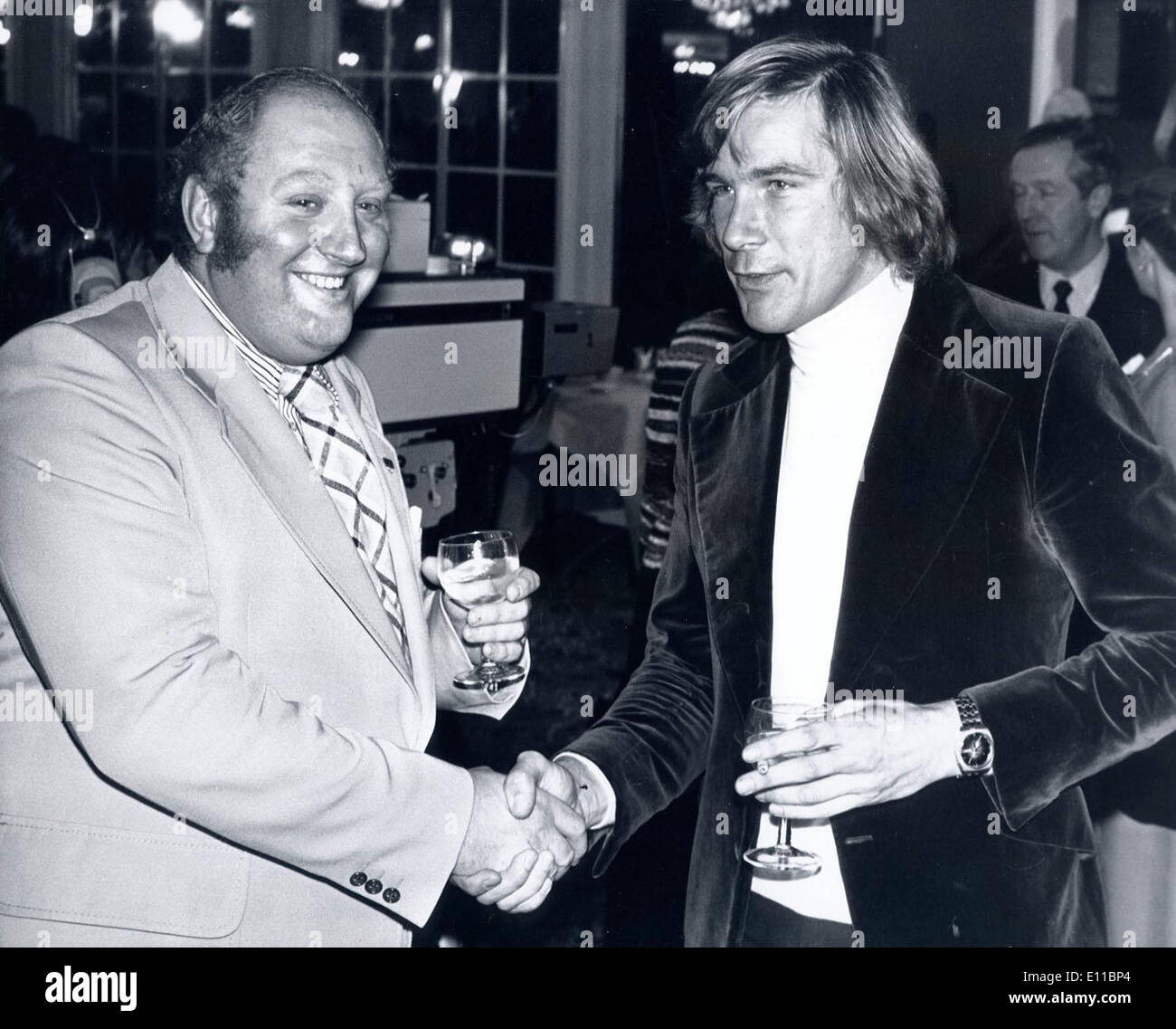 Dec 06, 1976 - Londres, Angleterre, Royaume-Uni - GERRY MARSHALL (L) et James Hunt se serrer la main à l'hôtel Royal Lancaster to show il n'y a aucun ressentiment après Hunt vendredi dernier à pointe accidentellement un verre de gin dans le visage de Marshall et lui coupe avec le verre. Banque D'Images