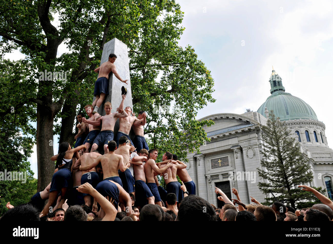 US Naval Academy freshmen connu sous le nom de plèbe, grimper le Monument Herndon, une tradition symbolisant la réussite de l'aspirants de première année le 19 mai 2014 à Baltimore, Maryland. La plèbe sans plus de cérémonie, implique de travailler ensemble pour monter le monument graissé et remplacer une tasse de dixie plebe hat sur le dessus avec une combinaison. C'est la fin officielle de la plebe année. Banque D'Images