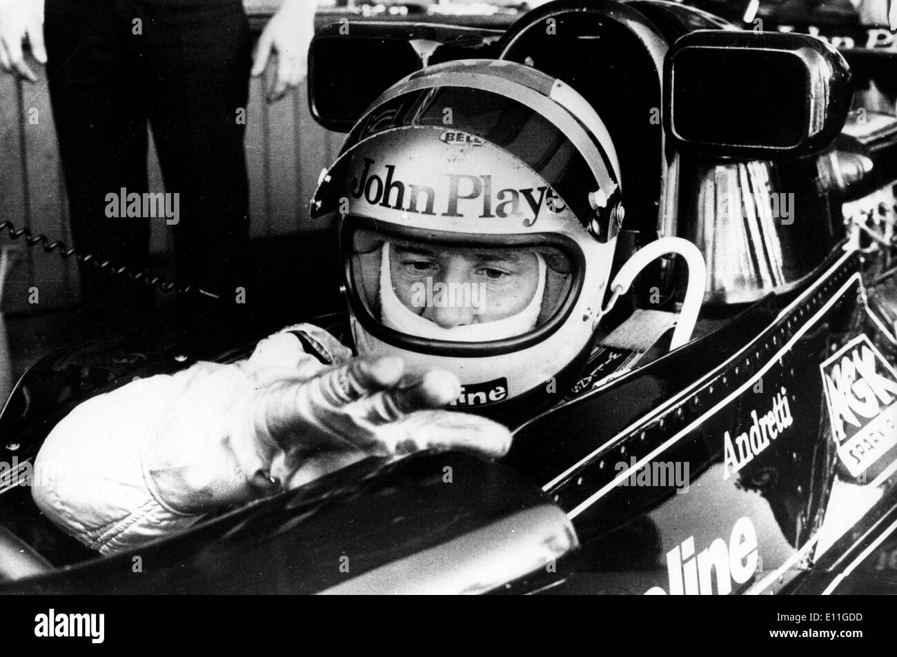 Pilote de course Mario Andretti assis dans son John Player Special Lotus, avant le départ de la course qu'il a gagné Banque D'Images