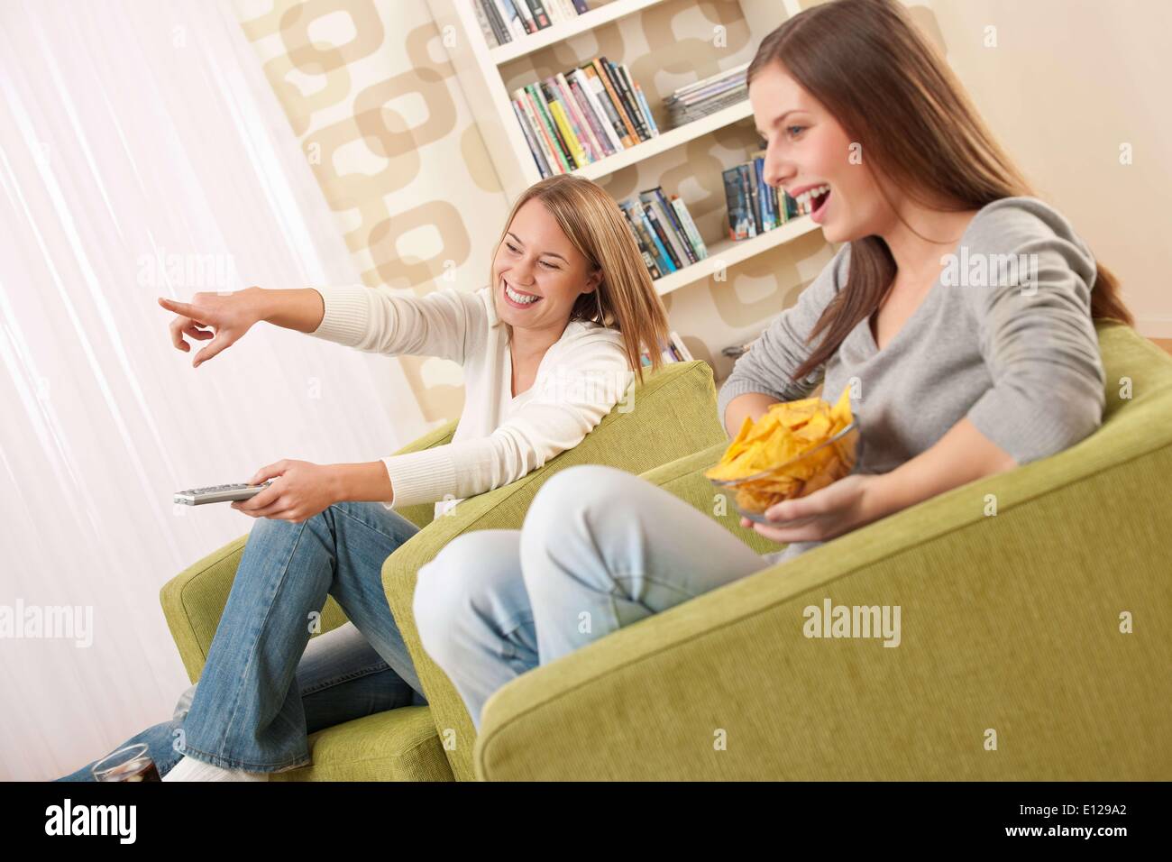 06 novembre 2009 - 6 novembre 2009 - Deux élèves - une adolescente à regarder la télévision et manger des chips dans un salon moderne Banque D'Images