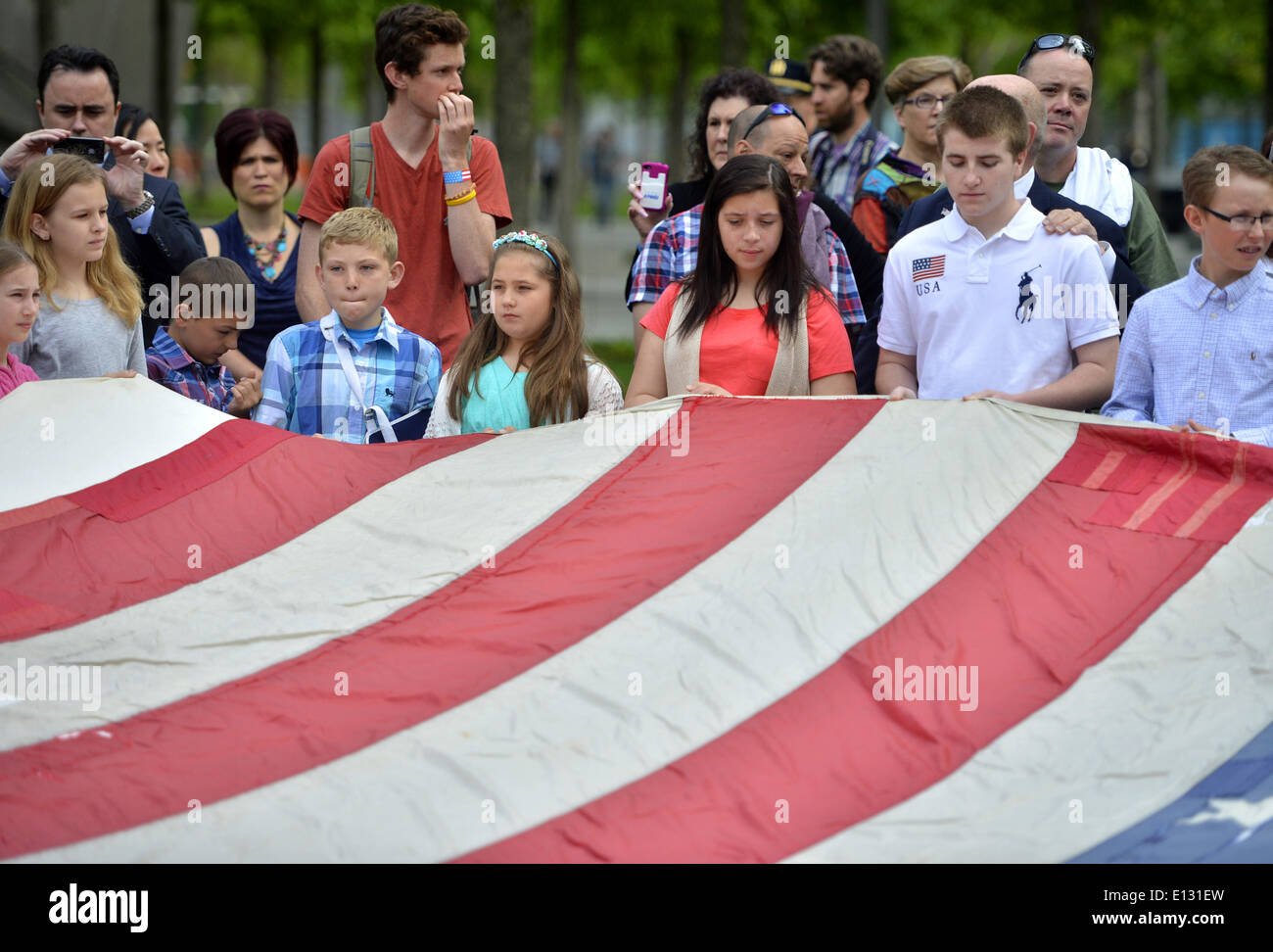 New York, USA. 21 mai, 2014. Les enfants occupent le drapeau national le 11 septembre devant le Musée Mémorial National du 11 septembre à New York, États-Unis, 21 mai 2014. Le Memorial Museum le mercredi ouvert au public après une cérémonie de transfert du drapeau national le 11 septembre, un drapeau américain qui avait flotté au 90 West Street, à côté de Ground Zero, pendant des semaines après les attaques, dans la collection permanente du musée. Credit : Wang Lei/Xinhua/Alamy Live News Banque D'Images