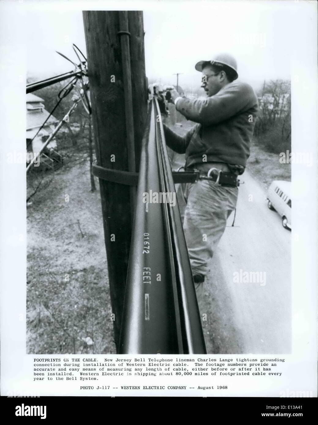29 février 2012 - Des traces de pas sur le câble. New Jersey poseur de Téléphone Bell Charles Lange resserre connexion de mise à la terre au cours de l'installation de câbles électriques de l'Ouest. Les numéros de séquence de façon exacte et facile moyen de mesurer toute la longueur du câble, soit avant ou après qu'il a été installé. La Western Electric est voyage environ 80 000 kilomètres de câble d'footprinted chaque année pour le système de Bell. Banque D'Images