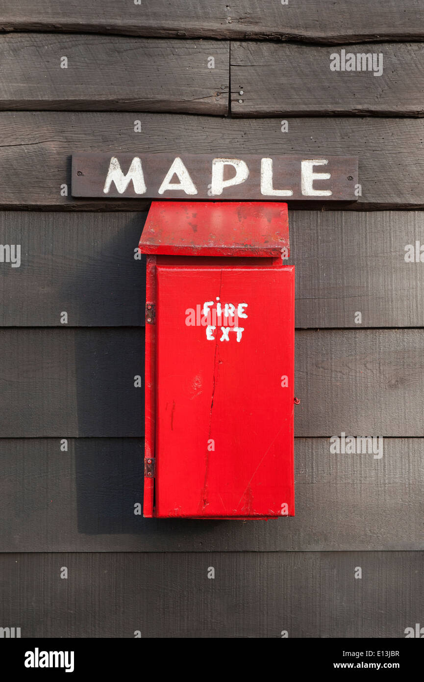 Boîte en bois rouge contenant un extincteur vissé sur le mur extérieur d'une cabane. Banque D'Images