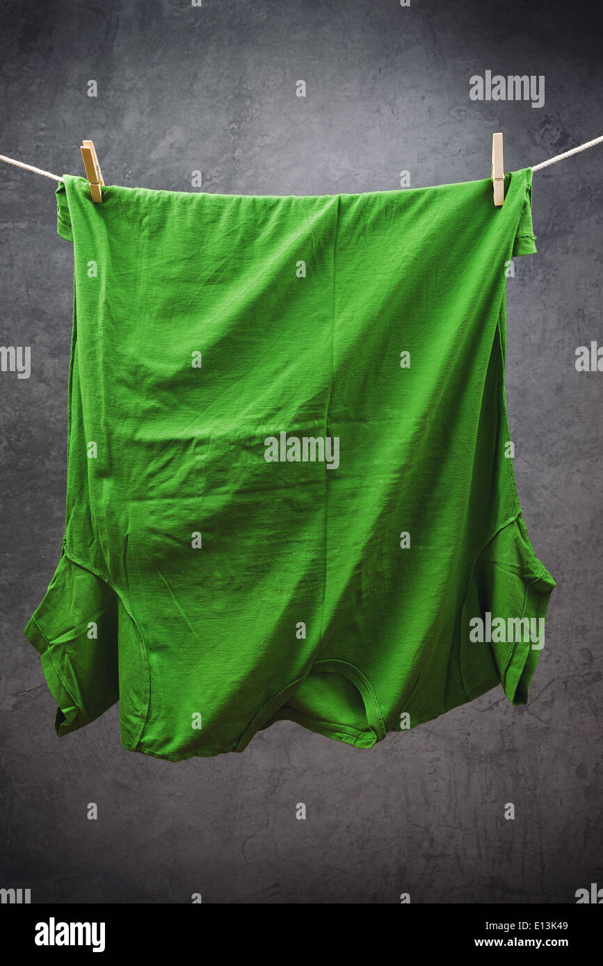 T shirt vert accroché sur corde à sécher, attaché avec des pinces à linge. Banque D'Images