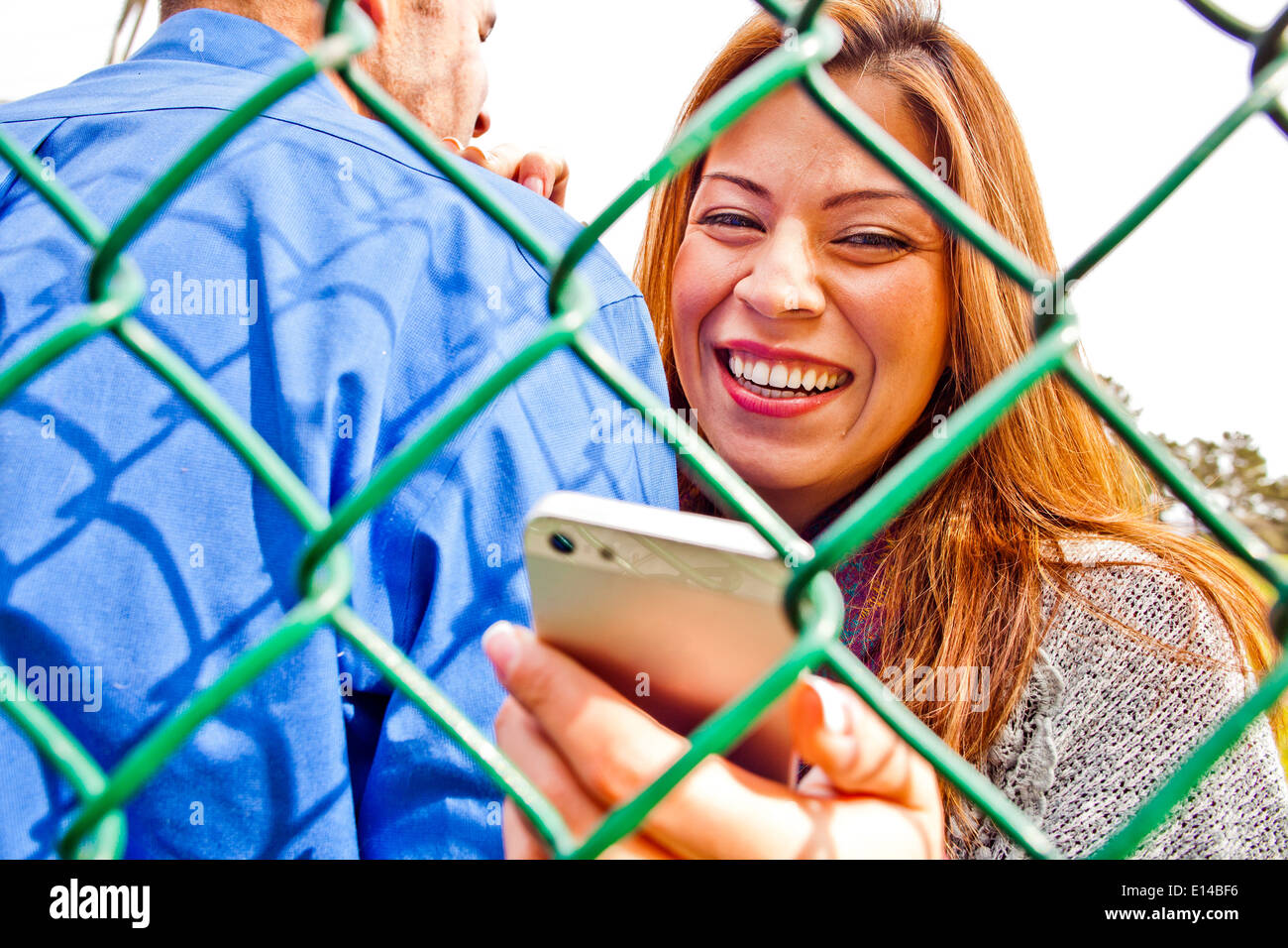 Hispanic woman with boyfriend using cell phone Banque D'Images