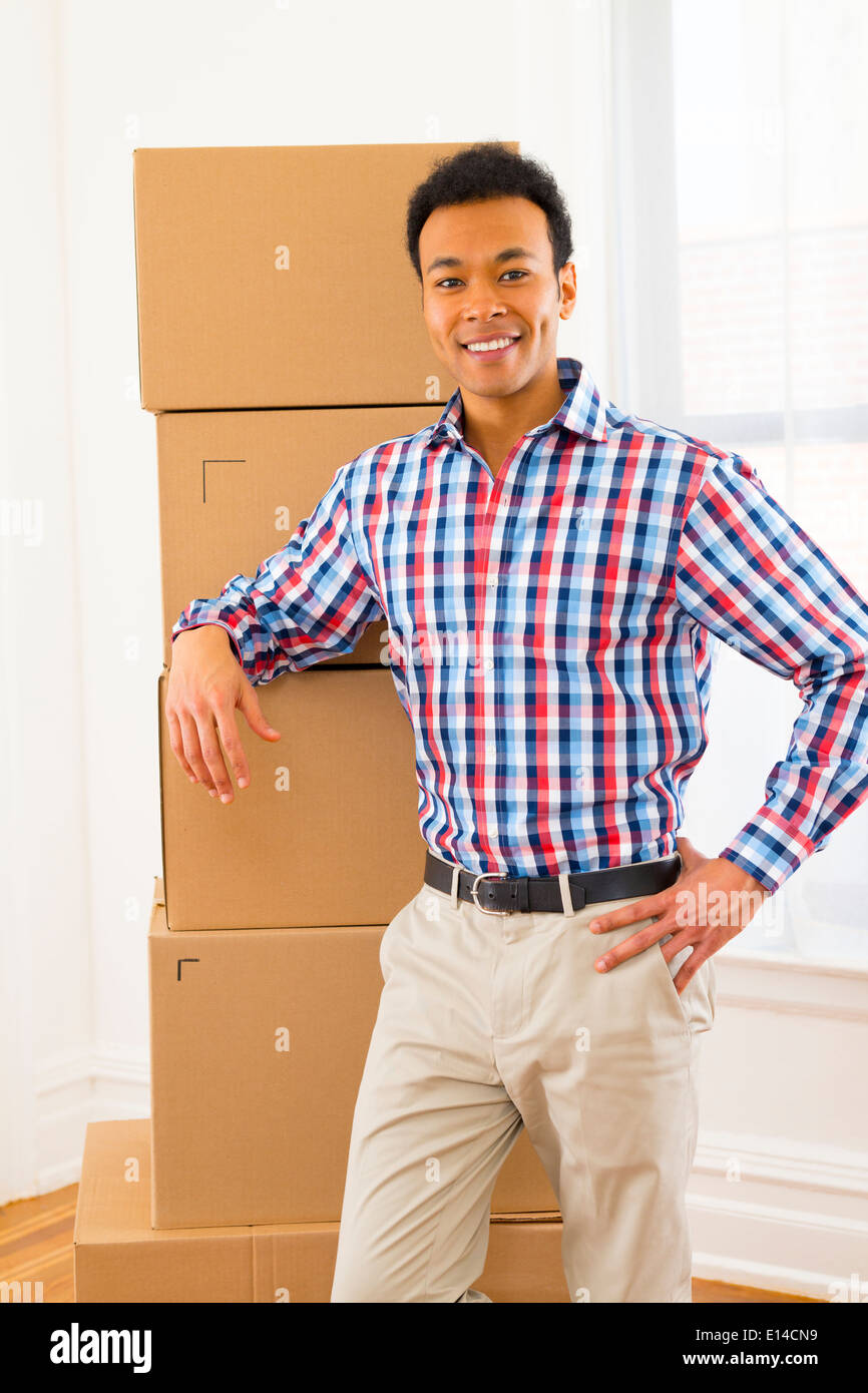 Mixed Race man standing par boîtes de carton à new home Banque D'Images