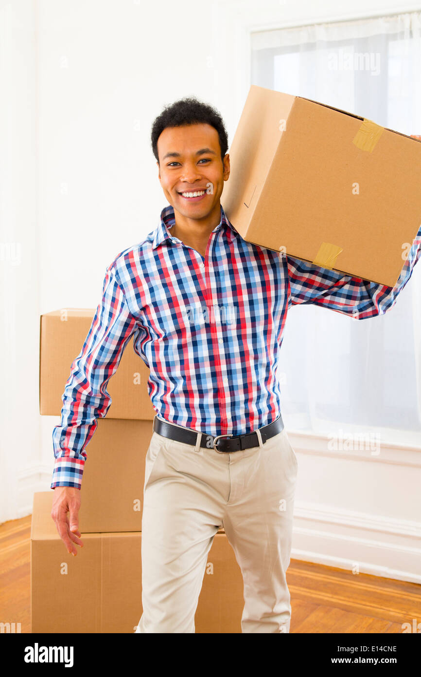 Mixed Race man carrying cardboard box in new home Banque D'Images