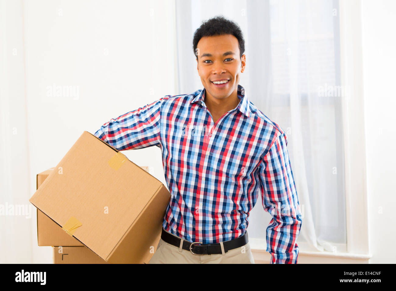 Mixed Race man carrying cardboard box in new home Banque D'Images