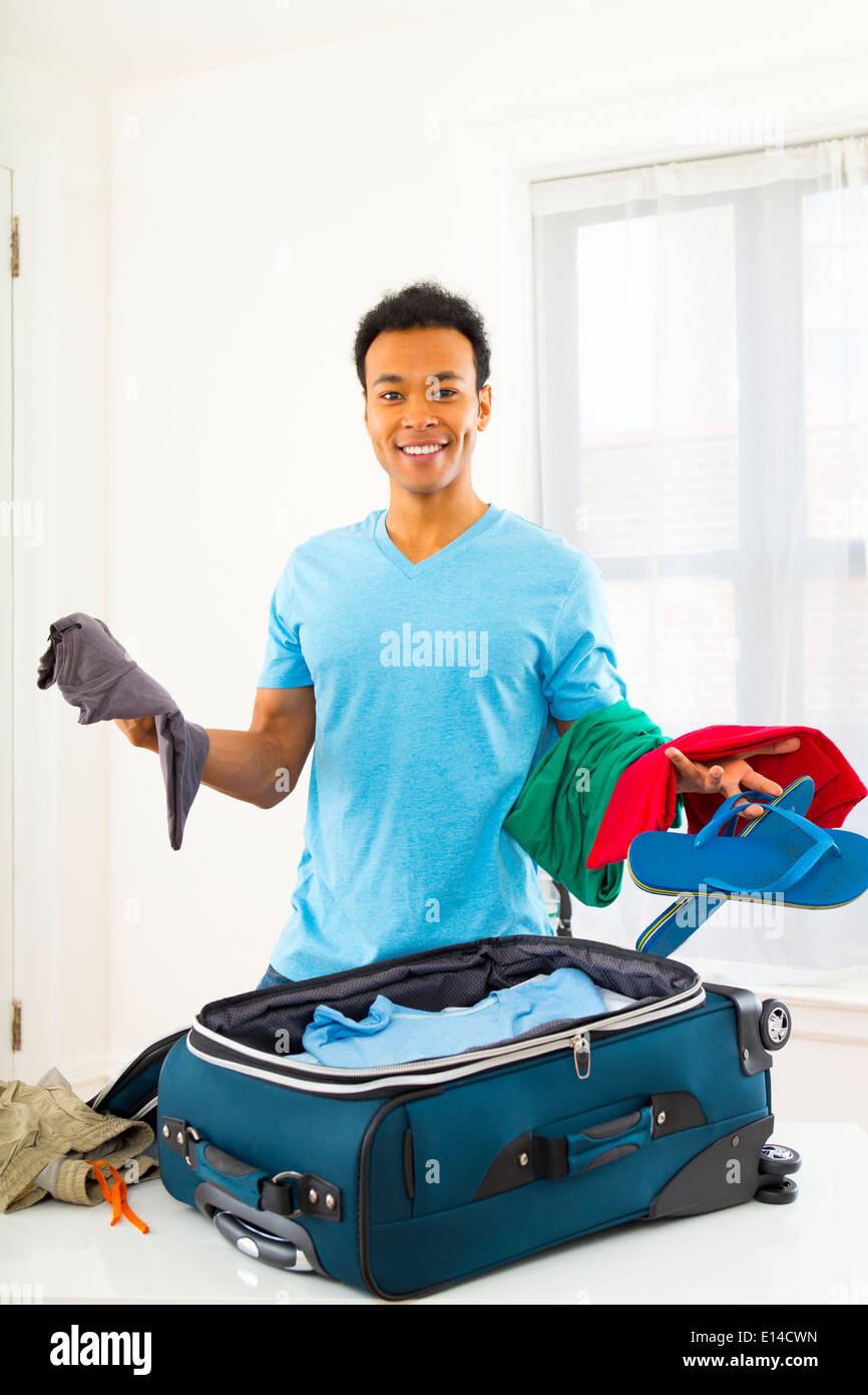 Mixed Race man packing suitcase Banque D'Images