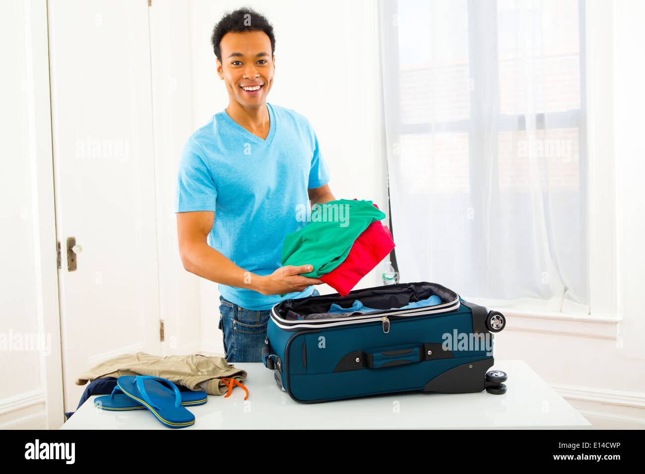 Mixed Race man packing suitcase Banque D'Images