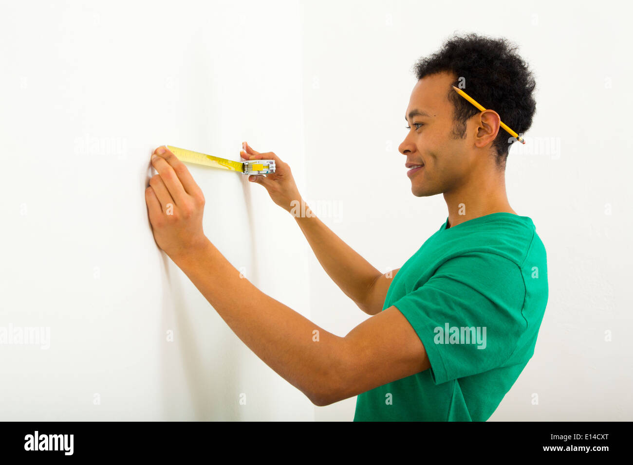 Mixed Race man measuring wall Banque D'Images