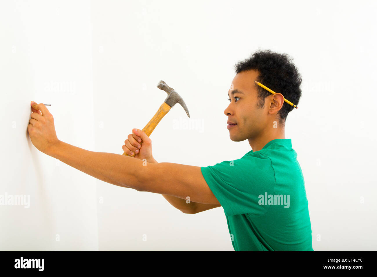 Mixed Race man hammering nail into wall Banque D'Images