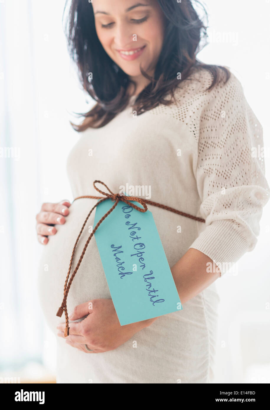 Pregnant Hispanic woman avec papier cadeau autour de ventre Banque D'Images