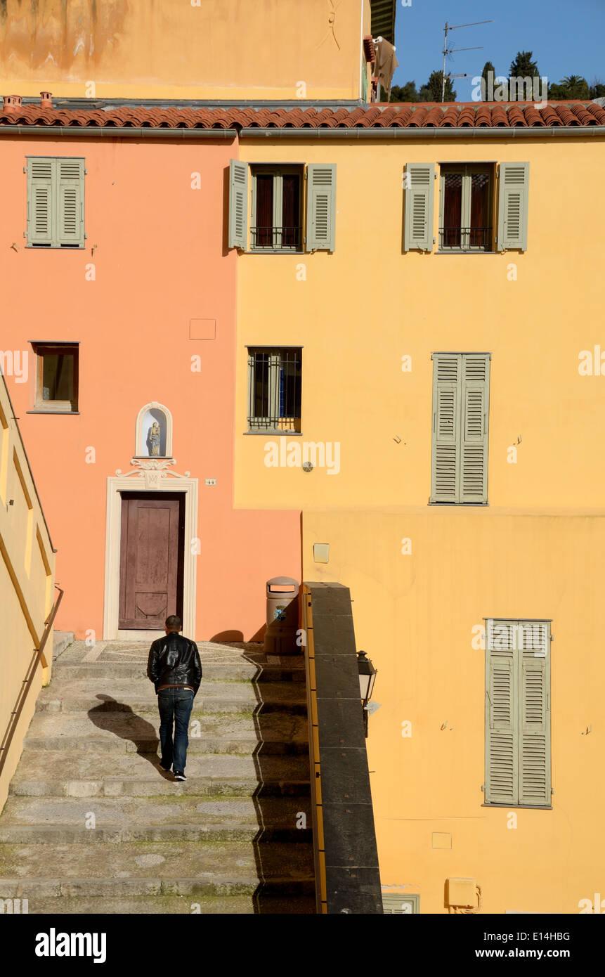 Man Climbing Steps dans la vieille ville et centre historique de Menton avec orange et jaune Maisons Menton Alpes-Maritimes France Banque D'Images