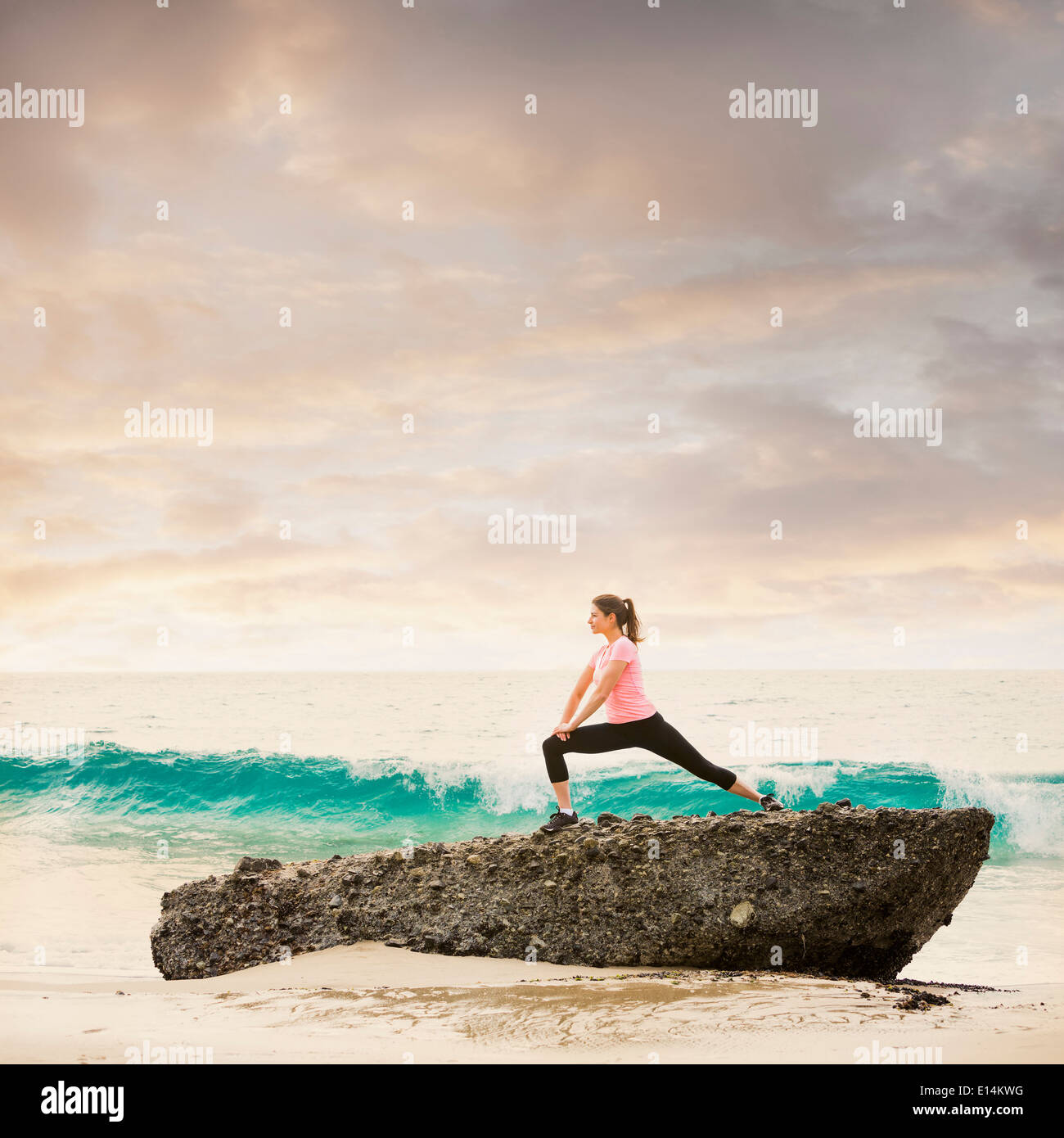 Caucasian runner stretching on beach Banque D'Images
