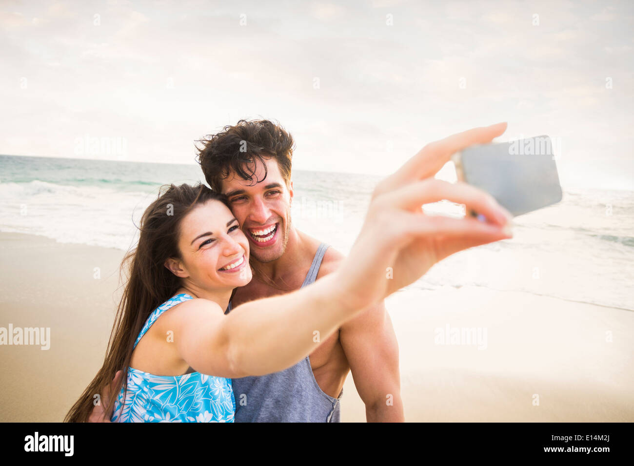 Caucasian couple taking pictures on beach Banque D'Images
