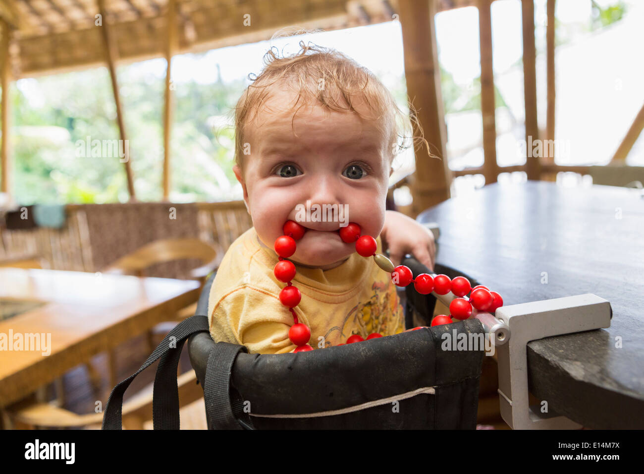 Portrait bébé jouant avec perles en chaise haute Banque D'Images