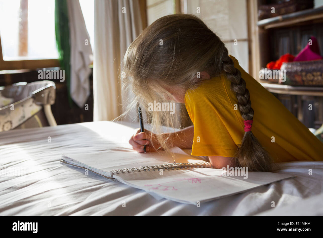 Caucasian girl dessin dans notebook on bed Banque D'Images