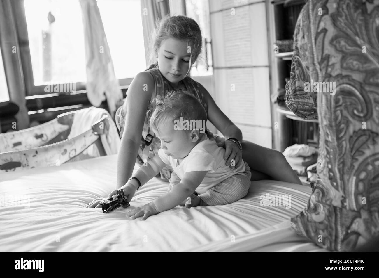 Caucasian girl et baby boy playing on bed Banque D'Images