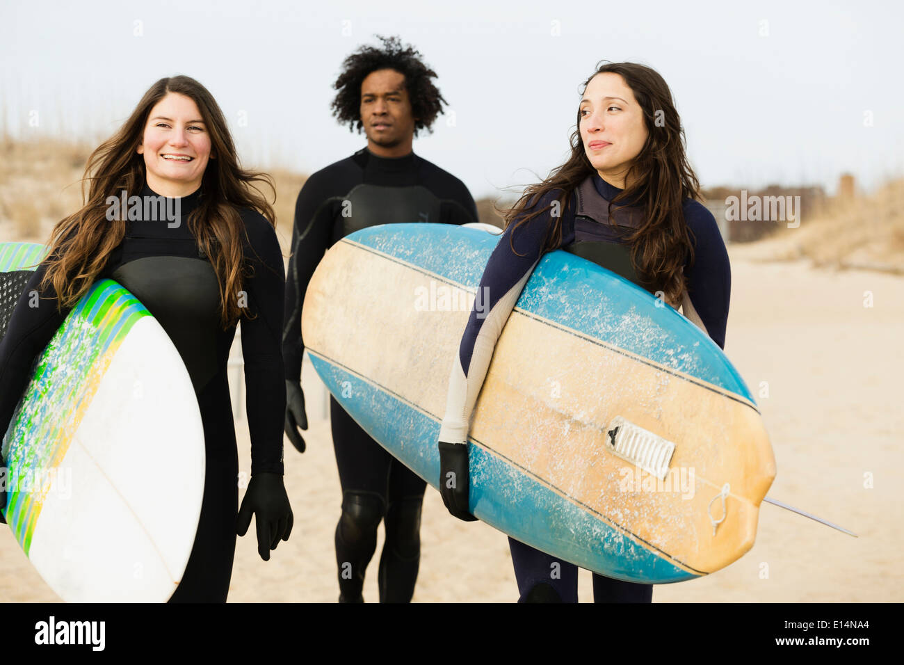 Surfers carrying boards on beach Banque D'Images