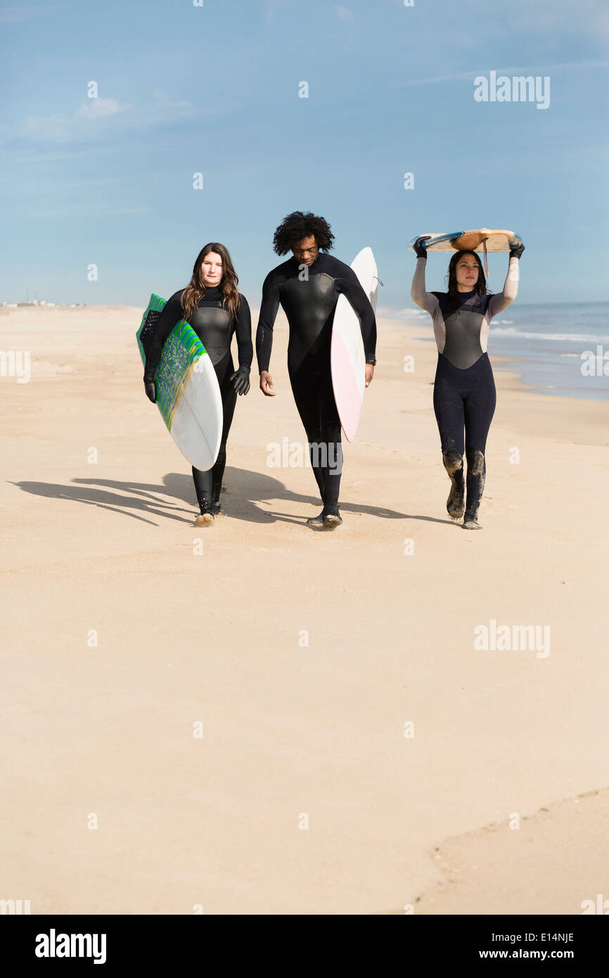 Surfers carrying boards on beach Banque D'Images