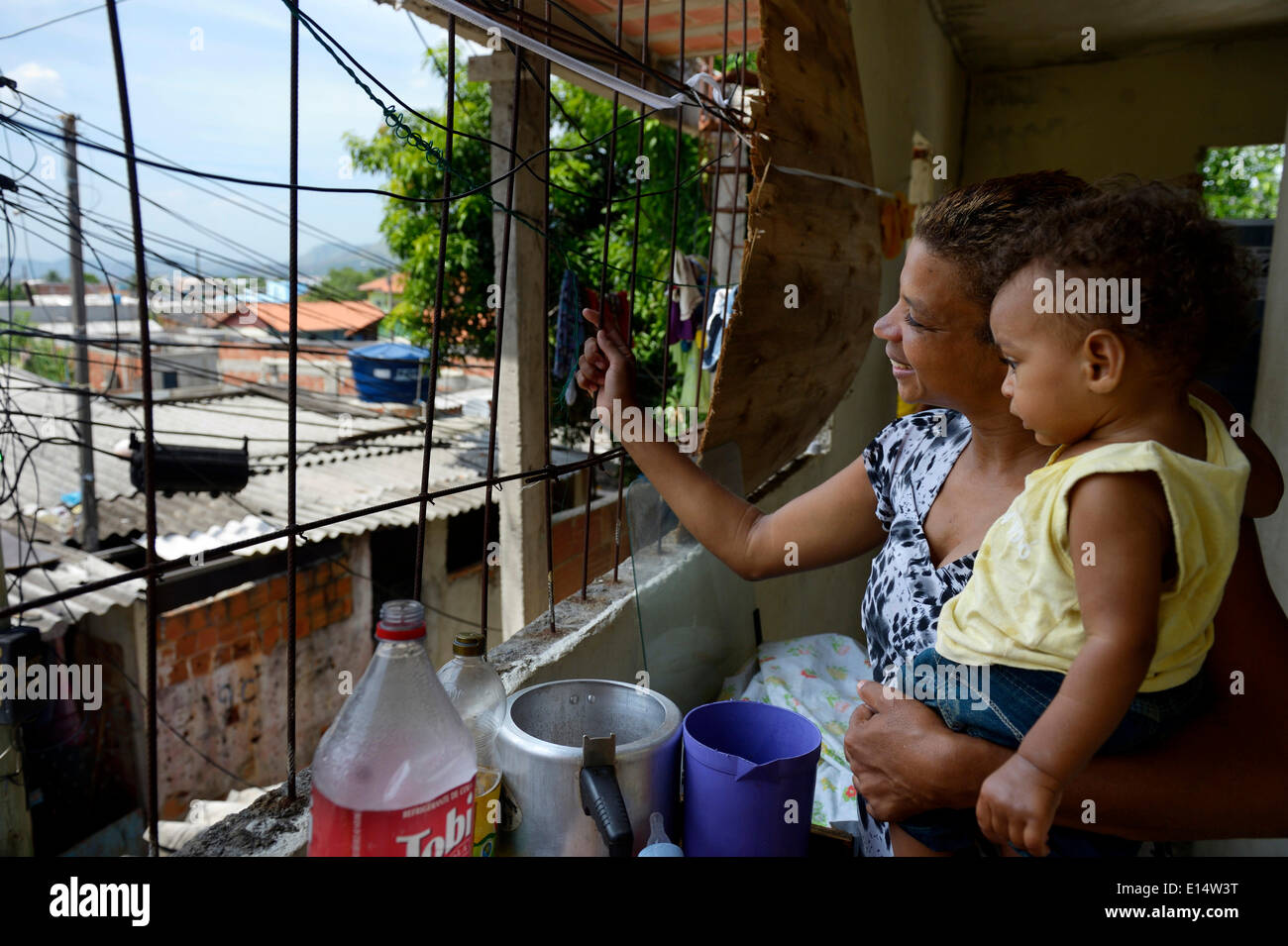 Femme, 38 ans, avec son fils, 1 ans, en regardant par la fenêtre de sa maison dans la favela Senador Camara, Rio de Janeiro Banque D'Images