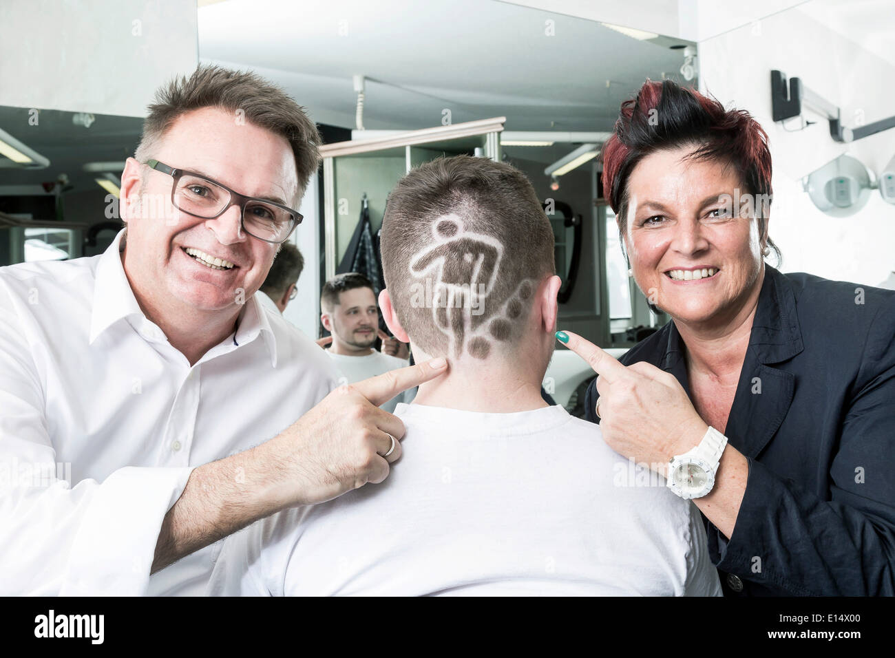 Les deux coiffeurs Gerhard Ostler et Sylvia Ostler posant avec un client qui a reçu une Coupe du Monde de Football tatouage cheveux Banque D'Images