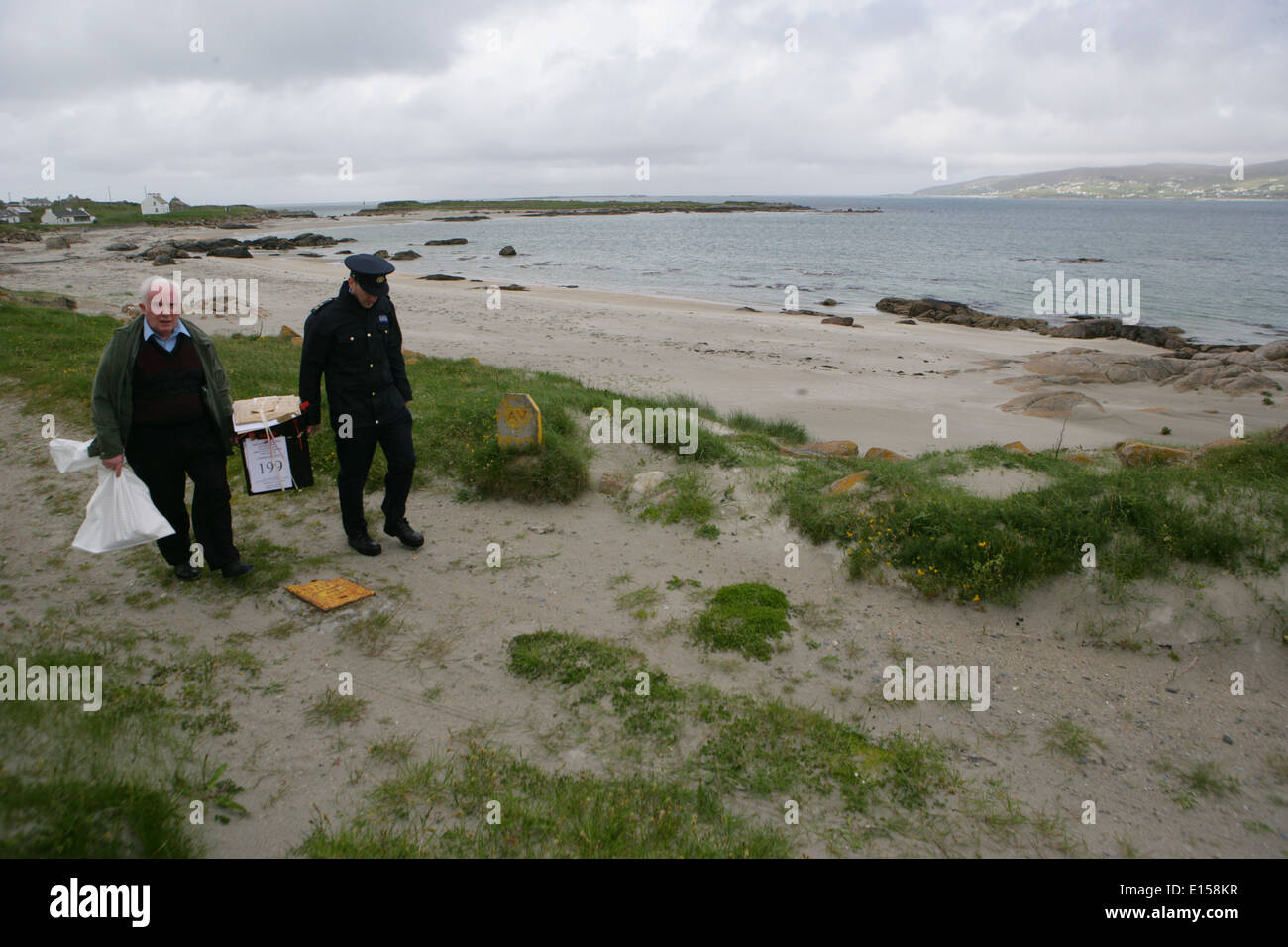 Président Hugh O'Donnell et officier de garde P.J. McHugh portent la boîte de scrutin à l'île de Innishfree, comté de Donegal, Banque D'Images