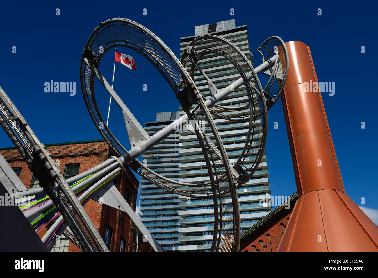 Batteur à oeufs et la sculpture à l'entonnoir Distillery District historique à Toronto avec drapeau canadien sur ciel bleu Banque D'Images