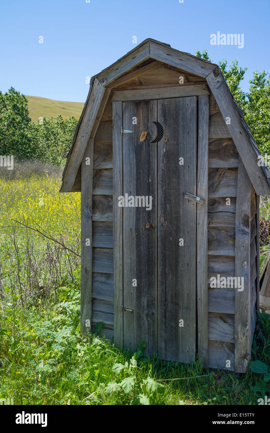 Une ancienne dépendance en bois avec une demi lune découpe dans la porte  dans un champ à l'extérieur de la communauté d'artistes de l'harmonie, en  Californie Photo Stock - Alamy