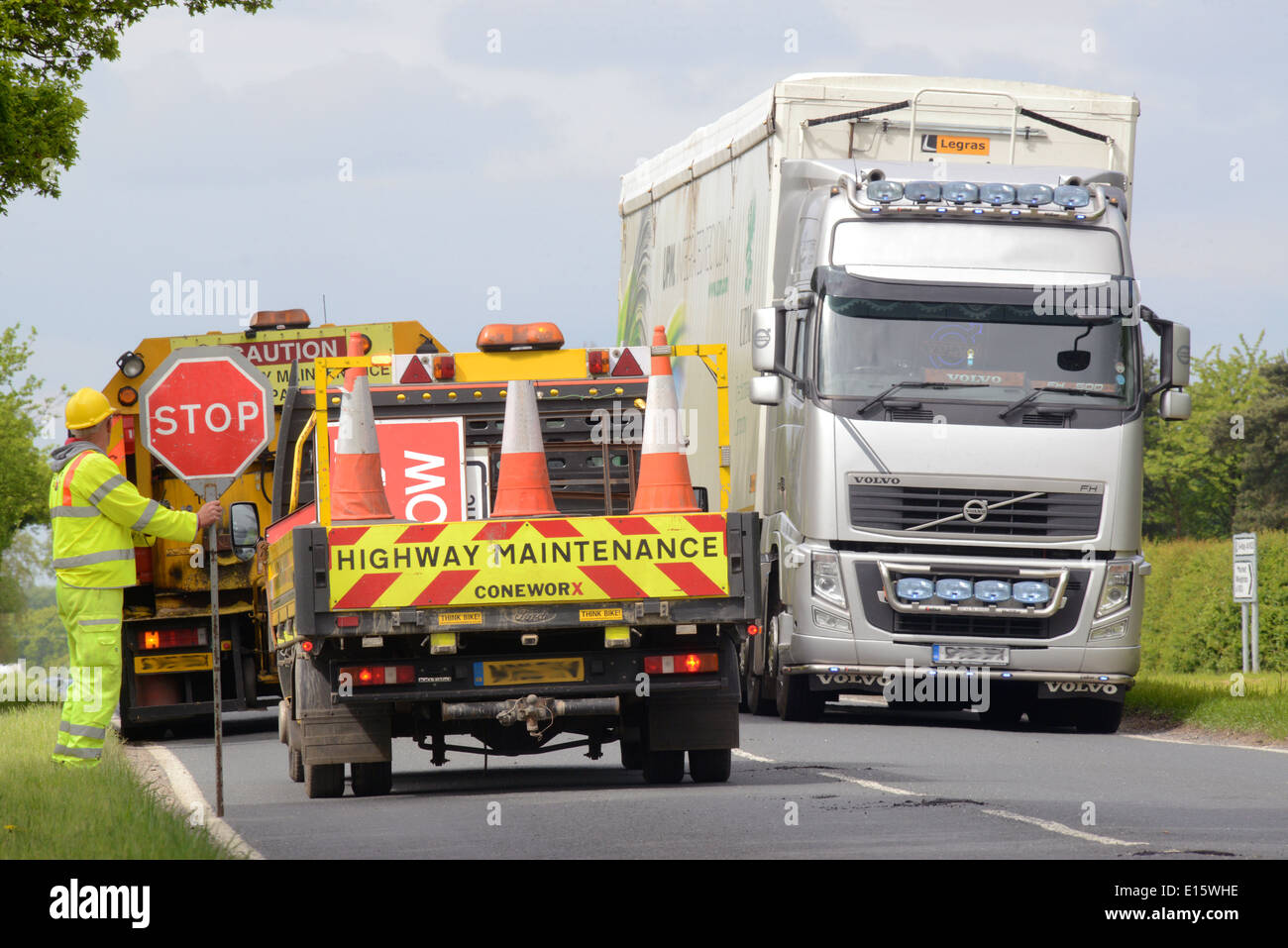 Travailleur de la construction à l'aide d'une sucette stop - rendez-vous signer pour contrôler le trafic au Royaume-Uni travaux routiers Banque D'Images