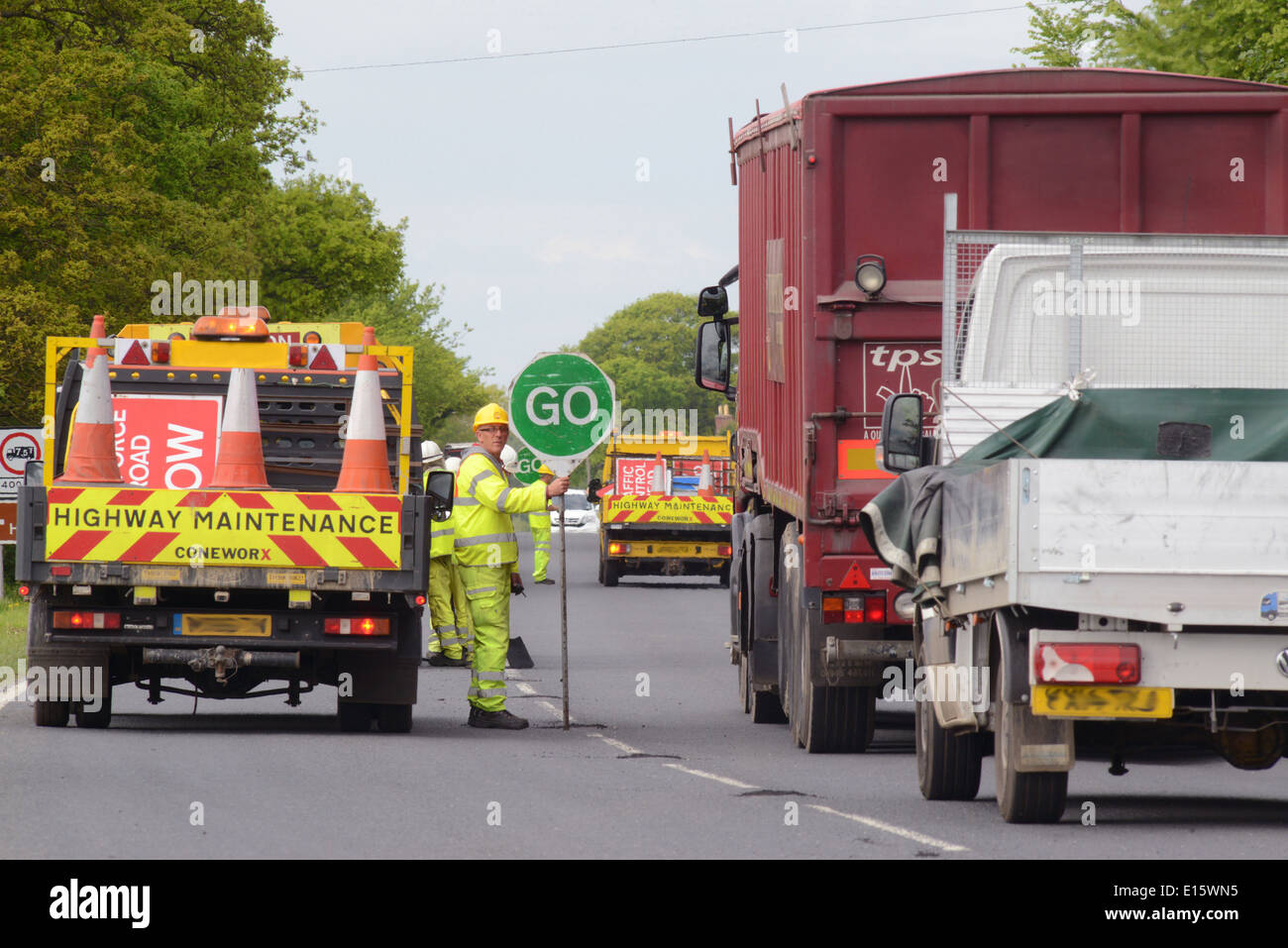 Travailleur de la construction à l'aide d'une sucette stop - rendez-vous signer pour contrôler le trafic au Royaume-Uni travaux routiers Banque D'Images