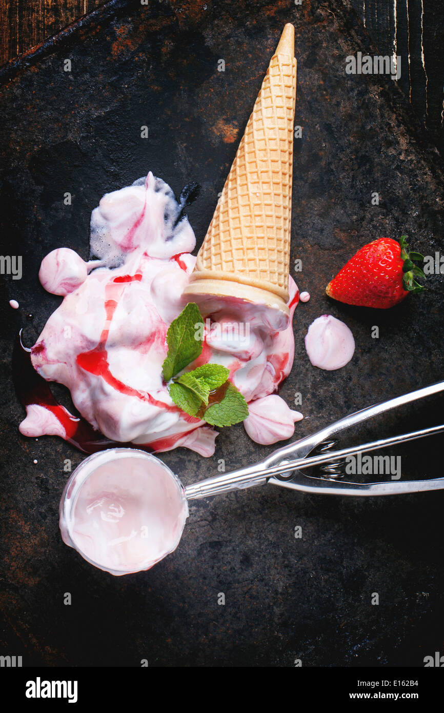 Wafer cone avec glace à la fraise avec des fraises fraîches, menthe et cuillère en métal sur le tableau noir. Banque D'Images