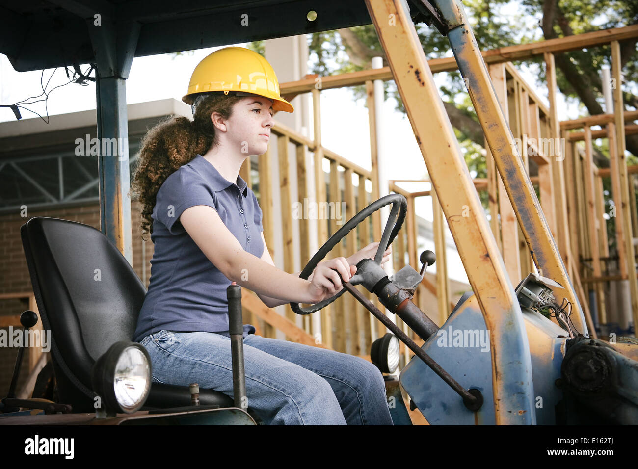 Young female construction apprenti l'apprentissage de la conduite d'équipement lourd. Banque D'Images