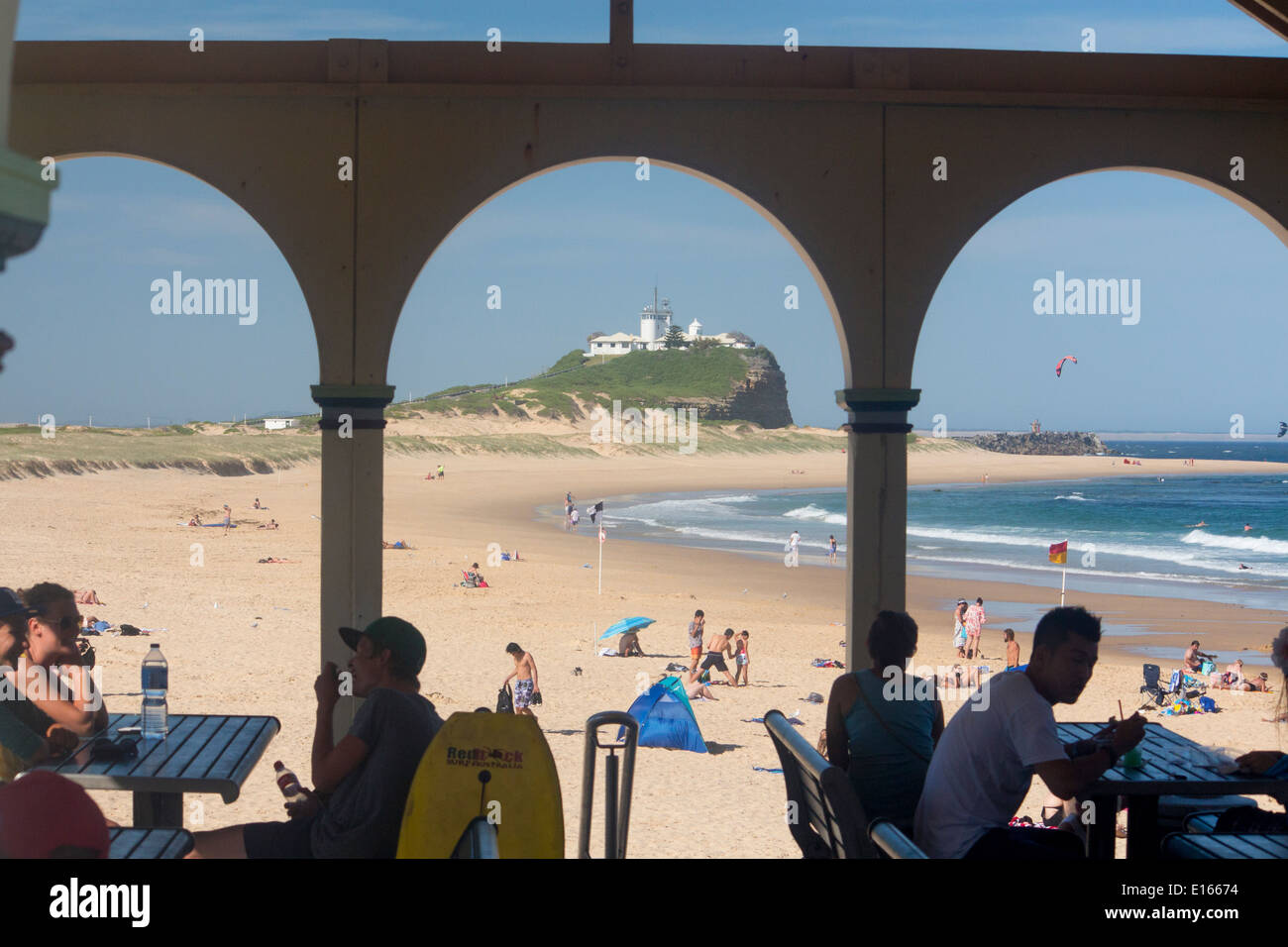 Plage de Nobbys Head et vu à travers arcades de pavilion et café avec des gens assis à des tables Newcastle Australie Nouvelle Galles du Sud Banque D'Images