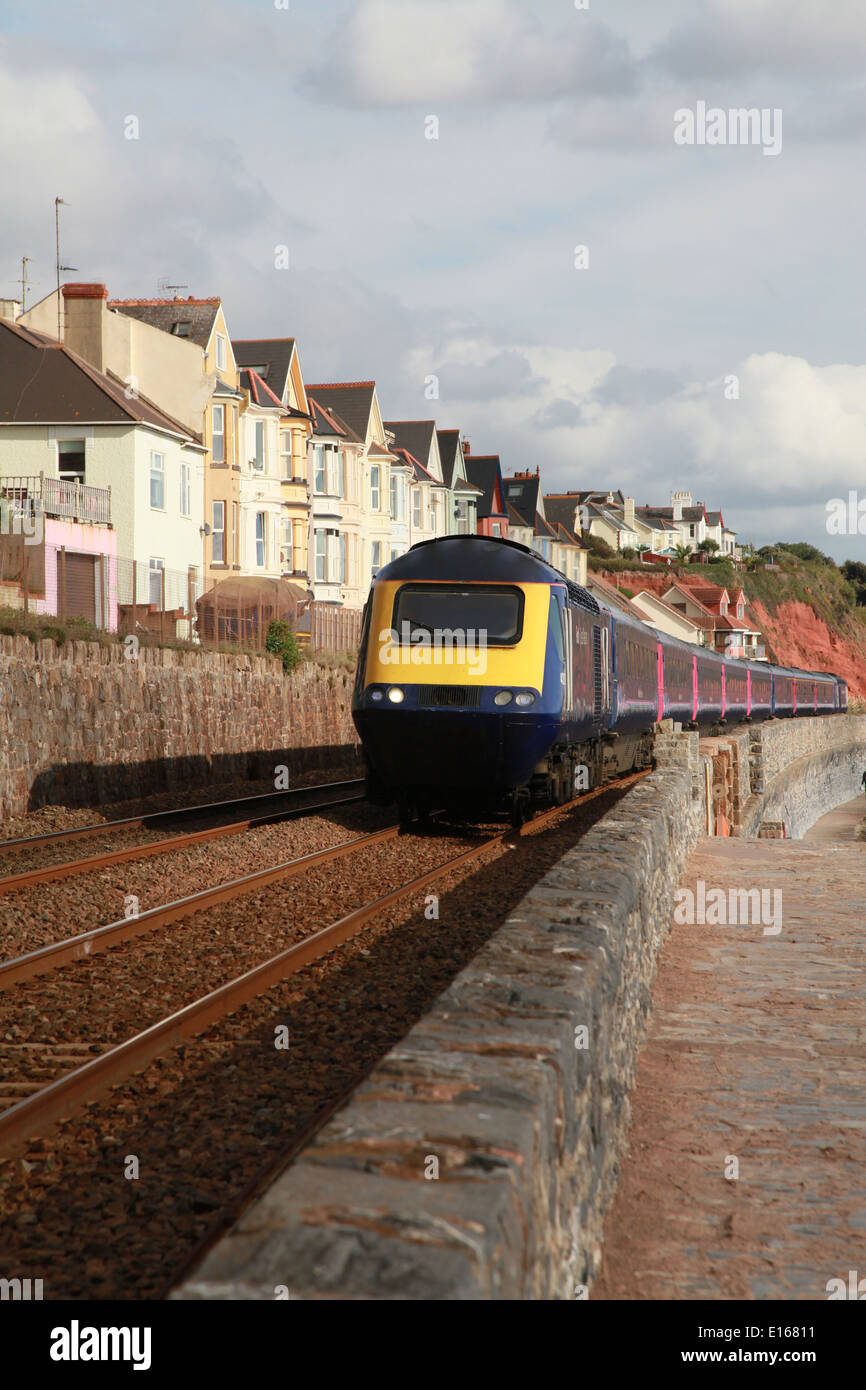 Une locomotive diesel approches avec une rangée de maisons victoriennes en arrière-plan Banque D'Images