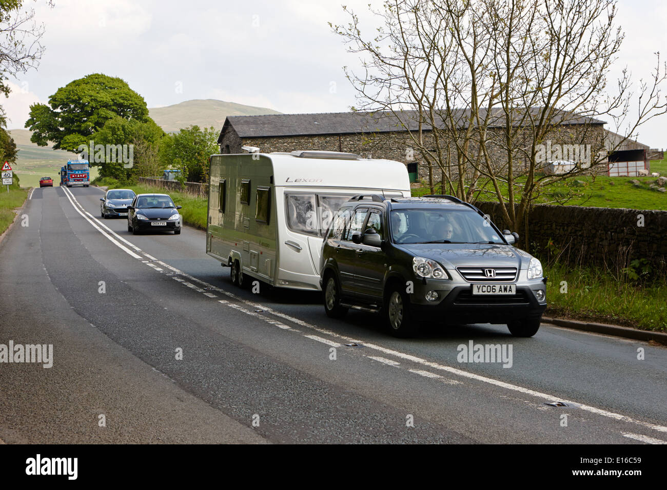 Les voitures d'attente derrière remorquage voiture caravane sur route A6 dans la région de Cumbria uk Banque D'Images