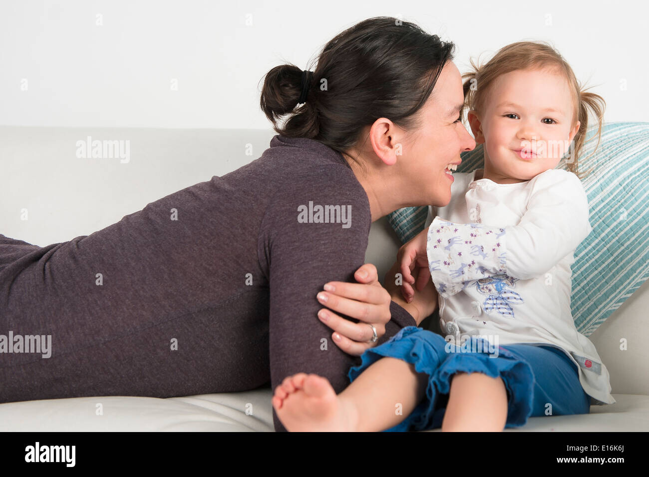 Mère avec little girl (2-3) sur le canapé blanc Banque D'Images
