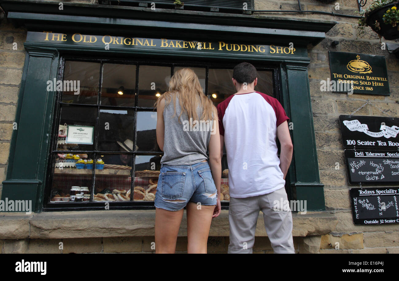 Un jeune couple s'arrêter pour regarder dans la fenêtre de l'ancien magasin de pudding Bakewell Original, Bakewell, Peak District, Derbyshire, Royaume-Uni peut Banque D'Images